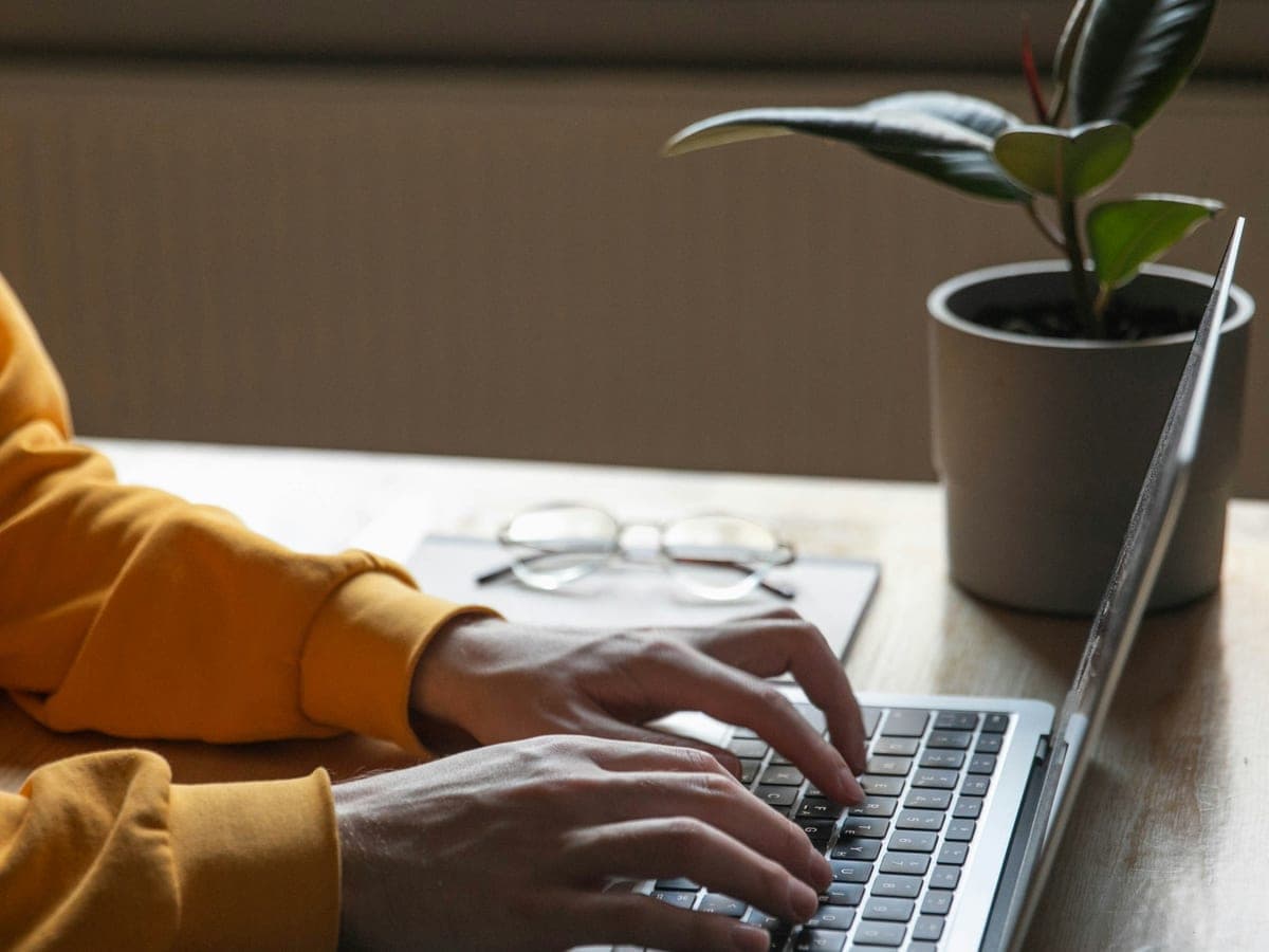 Des mains qui tapent sur un portable, à un bureau