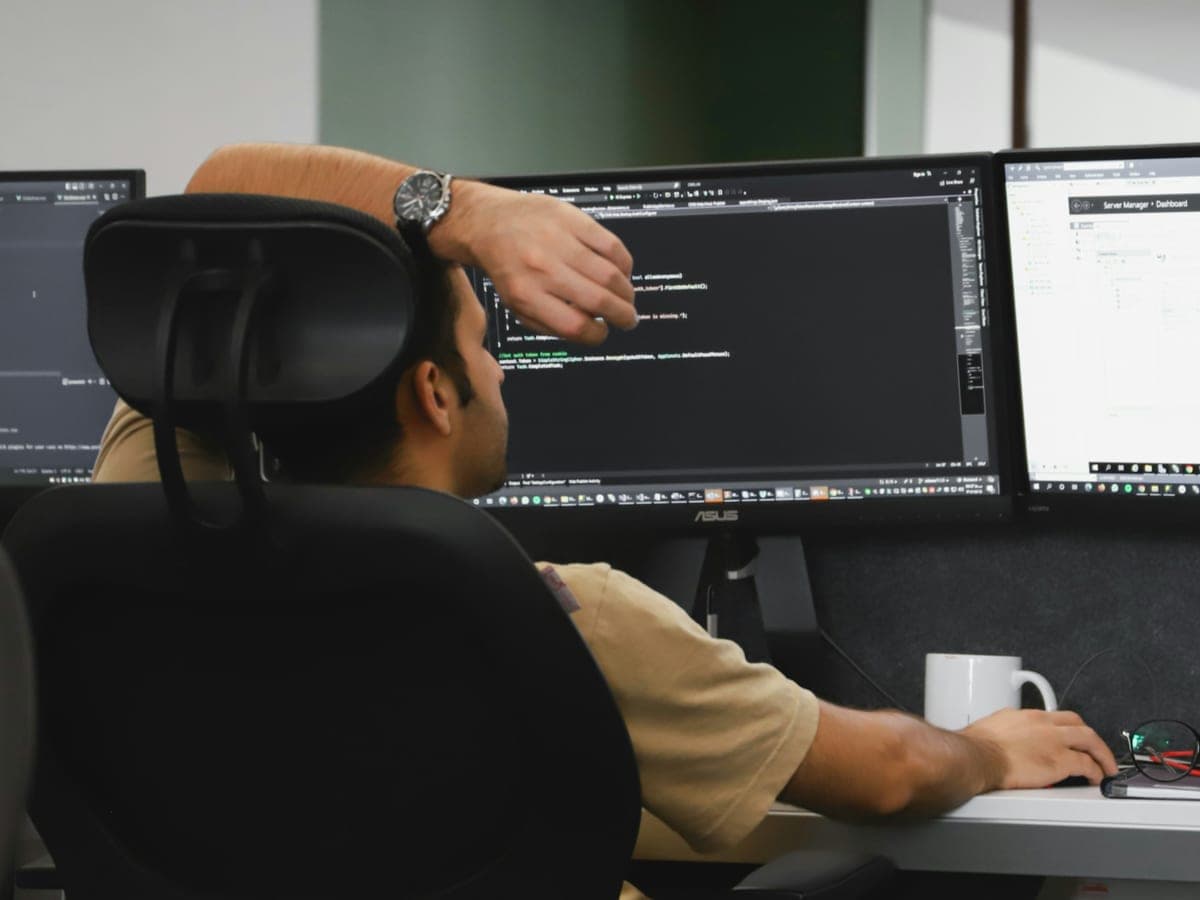 Un développeur travaillant sur du code applicatif sur deux écrans